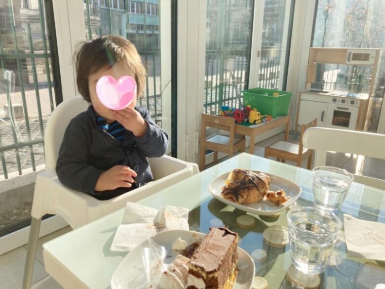 ブダペストにあるGeraldine-Augusztカフェのダイニングチェアに座ってクロワッサンを食べる息子
